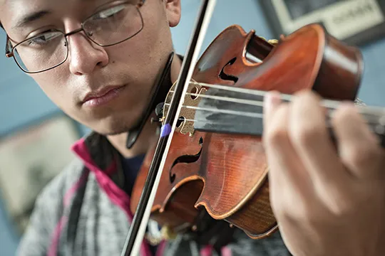 Student playing string instrument