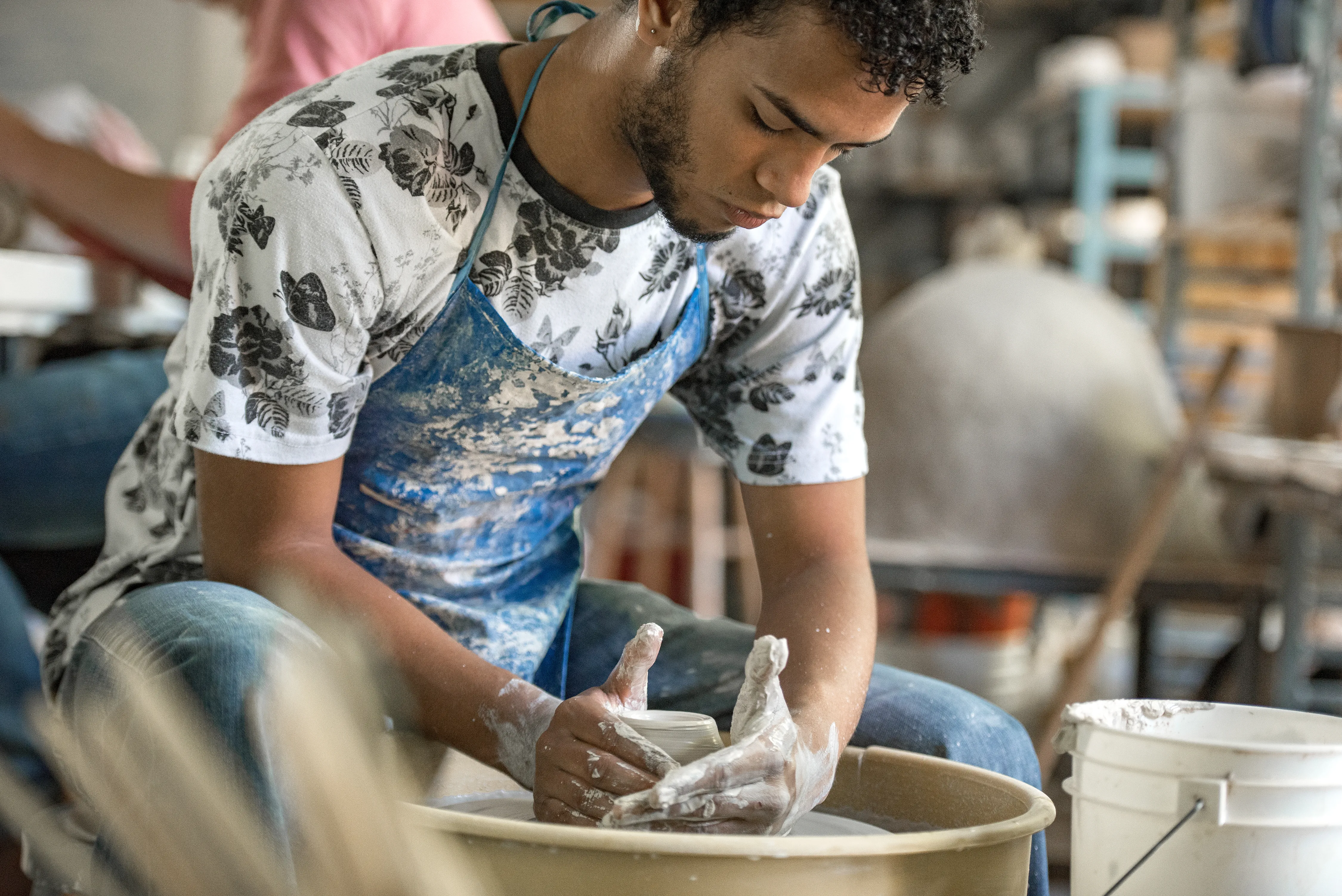 Male student working ceramics wheel
